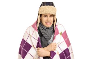 Young man covered with a blanket feeling cold isolated on white background