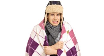 Young man covered with a blanket feeling cold isolated on white background