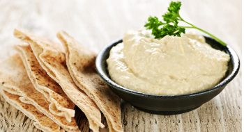 Bowl of fresh hummus dip with pita bread slices