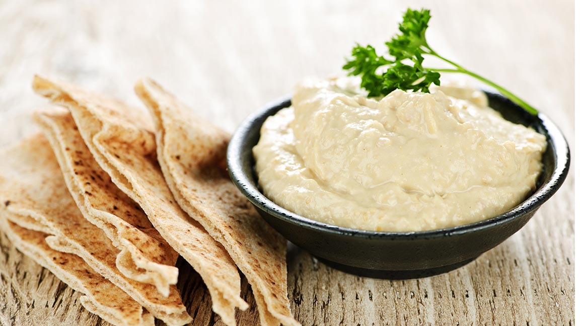 Bowl of fresh hummus dip with pita bread slices