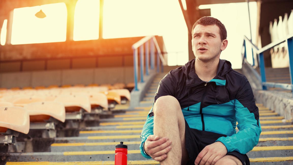 Runner sitting with bottle of water on the stairs at a stadium