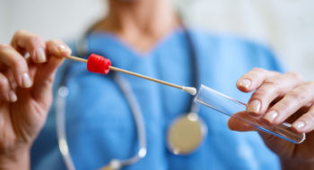 Nurse collecting DNA specimen from a test tube.