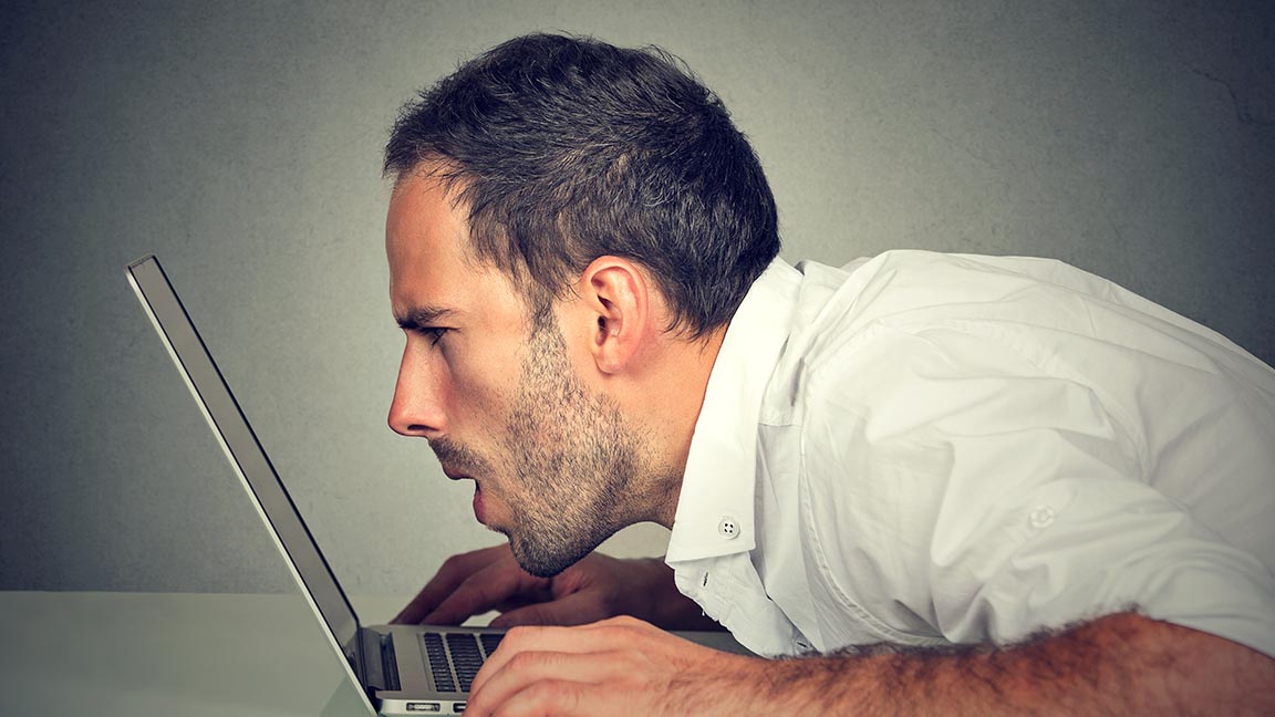 Man hunched over his computer in an ergonomically incorrect position.