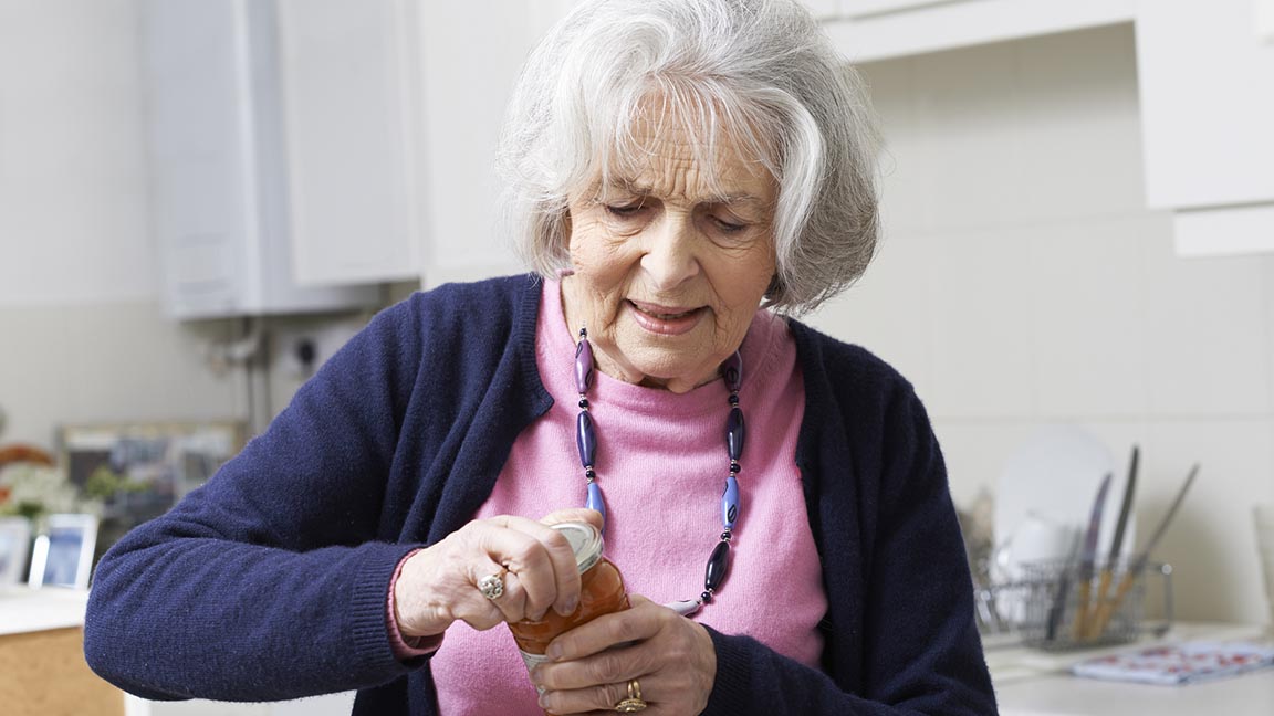 Woman struggles to open jar.