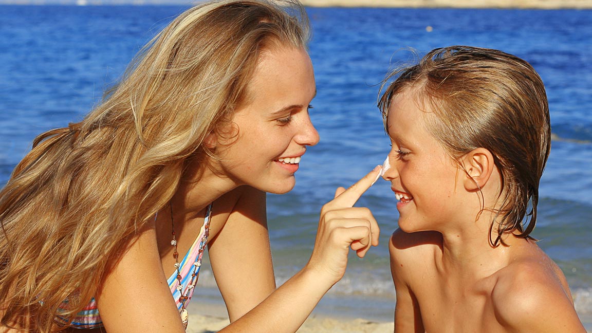 Brother and sister applying sunscreen