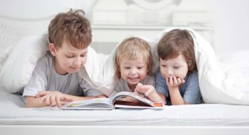 Three children read a book