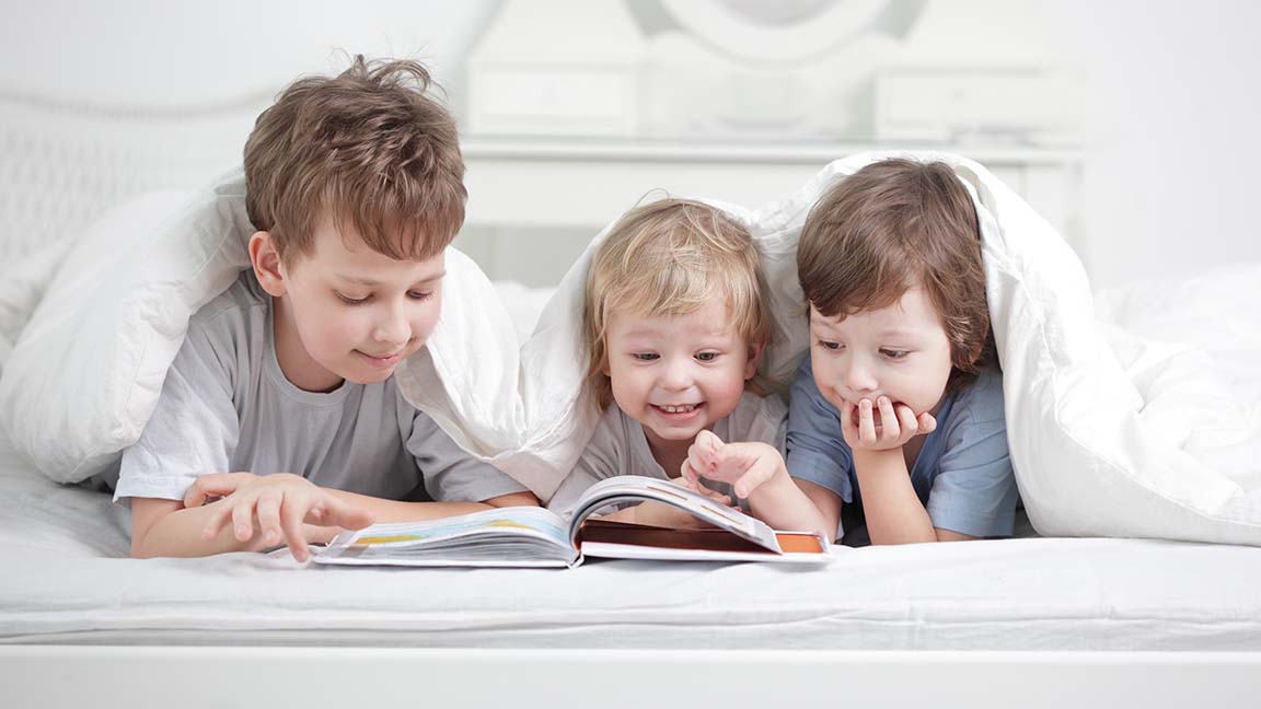 Three children read a book