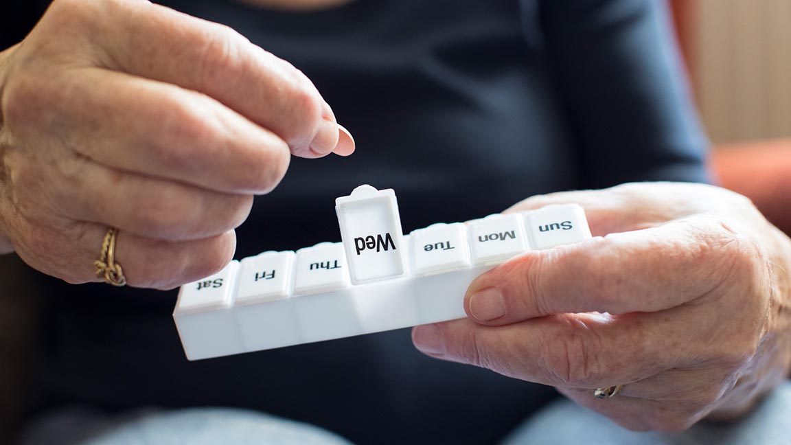 Woman Taking Medication From Pill Box