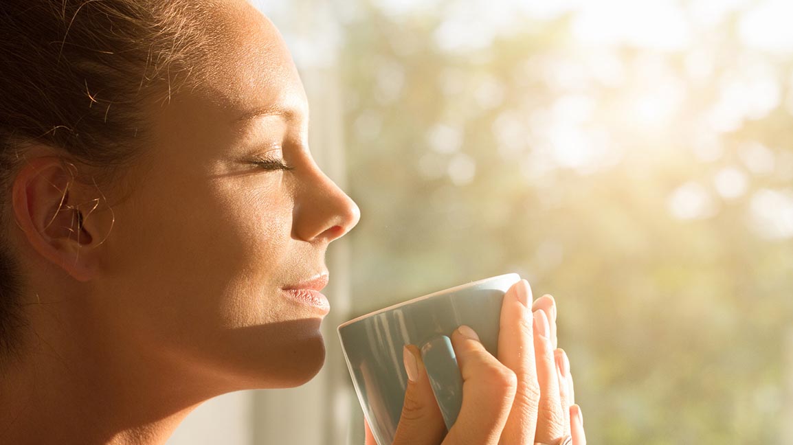 Woman enjoying coffee near a window.