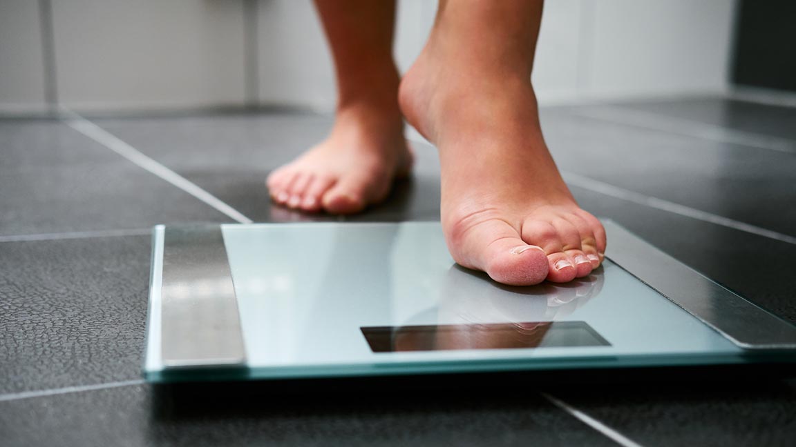 Individual with bare feet stepping onto scale