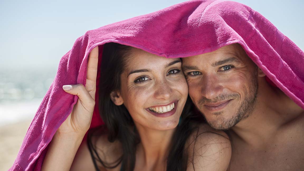 Couple on beach with towels on head.