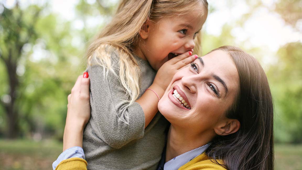 Mother and daughter outdoors in a meadow.