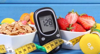 Glucometer with result of measurement sugar level, healthy food, dumbbells for fitness and tape measure, concept of diabetes, slimming, healthy lifestyle