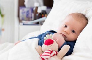 Newborn baby boy, lying in bed with cold and fever