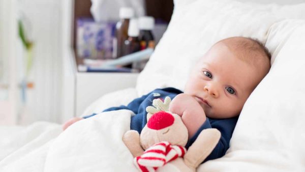 Newborn baby boy, lying in bed with cold and fever