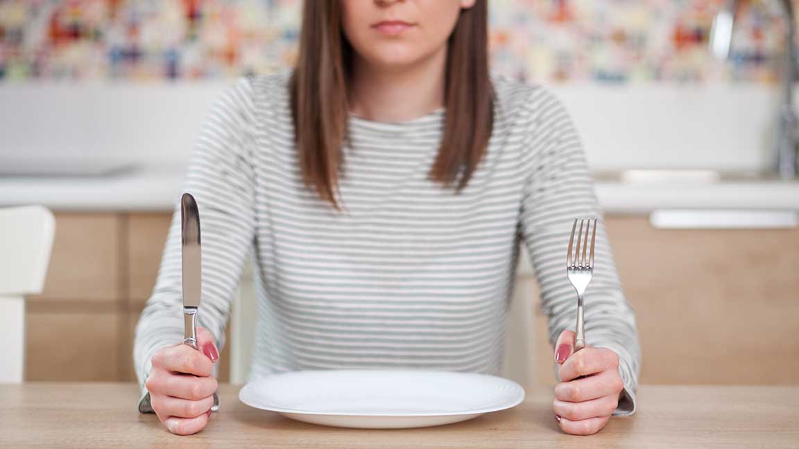Woman sitting before an empty plate