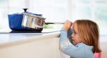 Child risks injury removing pan from stove.