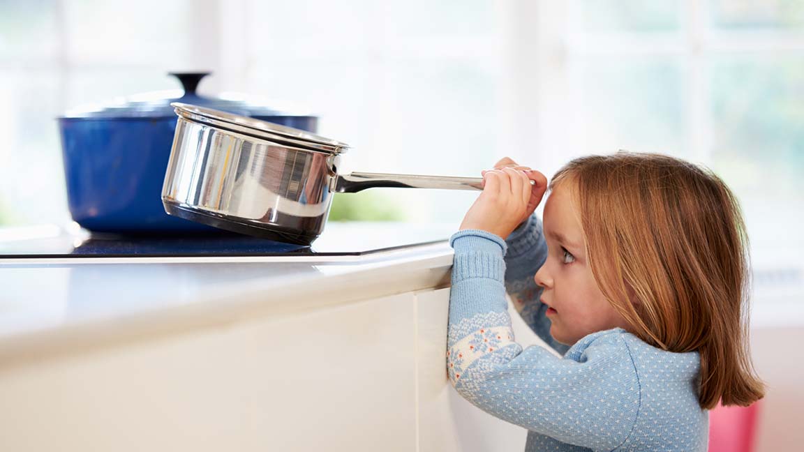 Child risks injury removing pan from stove.