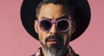 Portrait of a trendy man with silver beard, sunglasses and hat, isolated on pink studio background