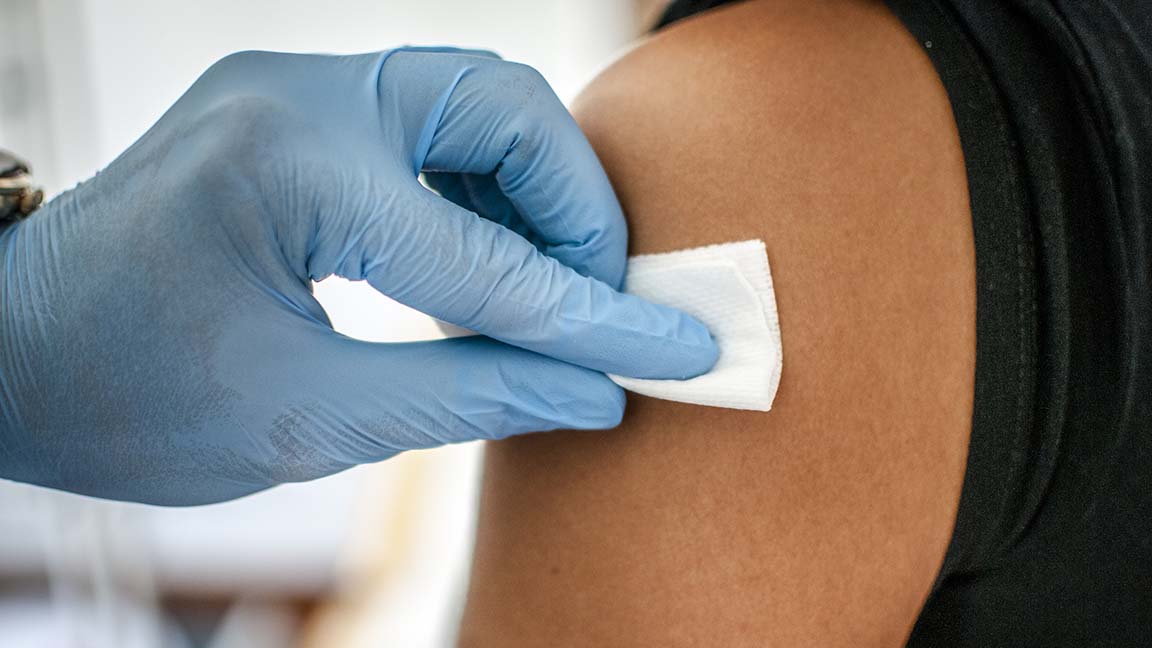 Doctor disinfects skin of patient before flu shot