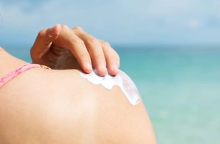 Woman applying sunscreen to shoulder