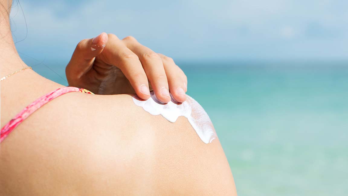 Woman applying sunscreen to shoulder