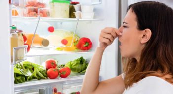 Young woman concerned about refrigerator smell.