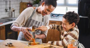 Son is helping mother to prepare pumpkin pie. American family. Single mother. Household chores for kids.