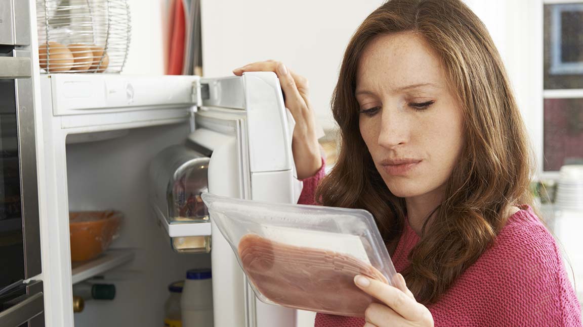 Concerned woman looks at meat.