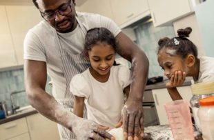 Father teaches daughters how to cook.