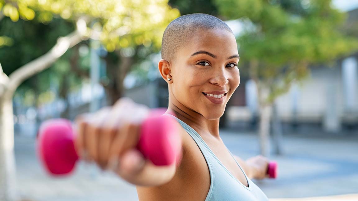 Woman exercising outside with weights