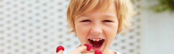 Delighted boy eating raspberries