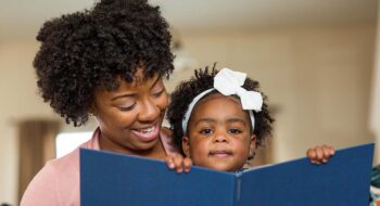 Woman reading book to child.