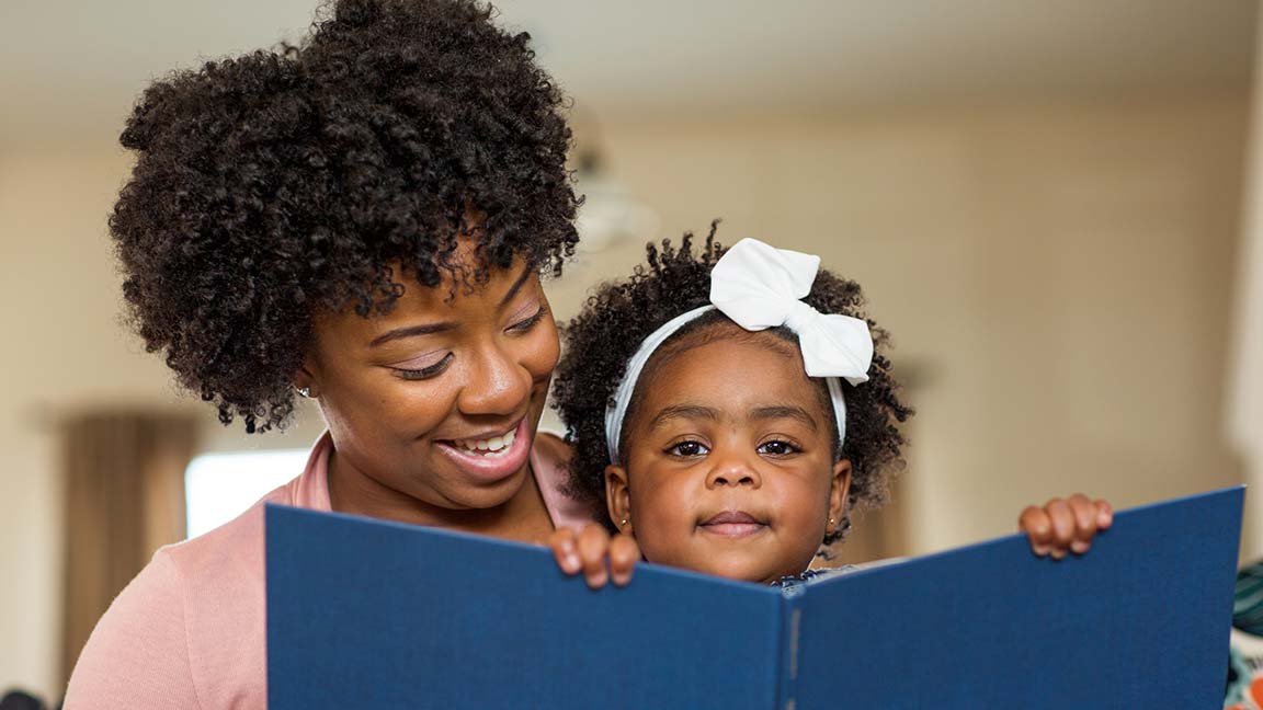 Woman reading book to child.