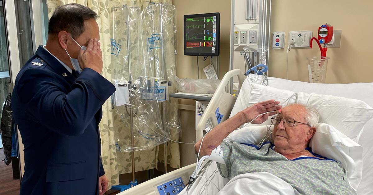 Tidelands Health family medicine physician Dr. Henry Lau in a hospital bed saluting another man in a military uniform.