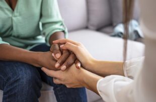 Closeup of two people holding hands.