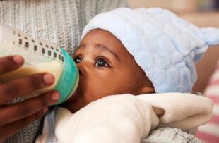 Infant drinks formula from a bottle.