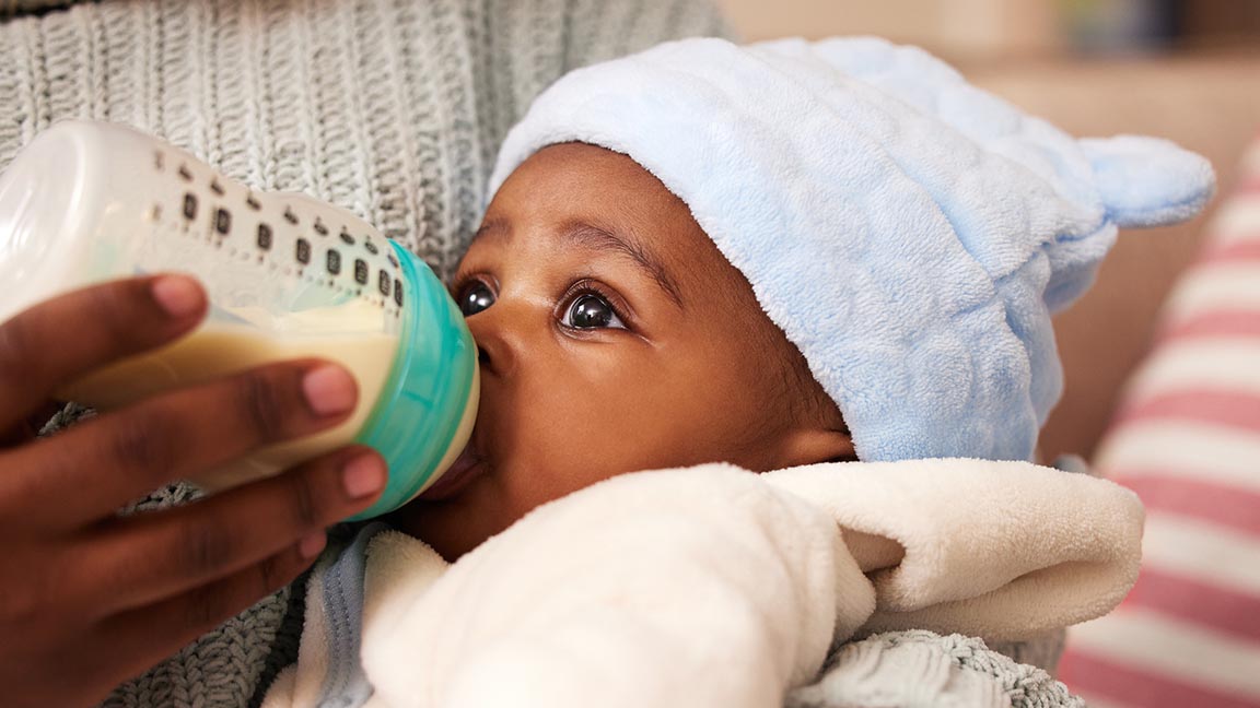 Infant drinks formula from a bottle.