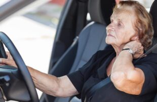 Senior woman driving with neck pain.