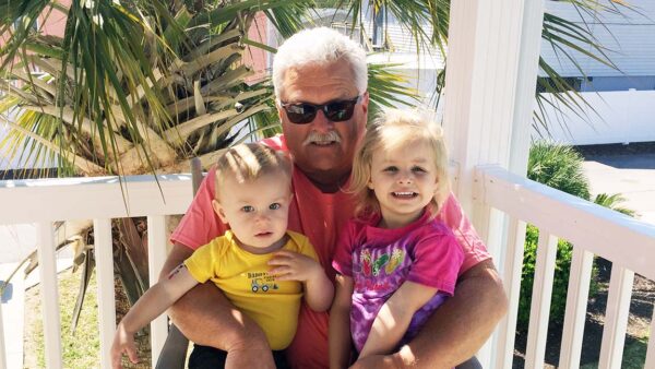 Murrells Inlet resident Joe Hofflinger smiling on a porch outside with two children