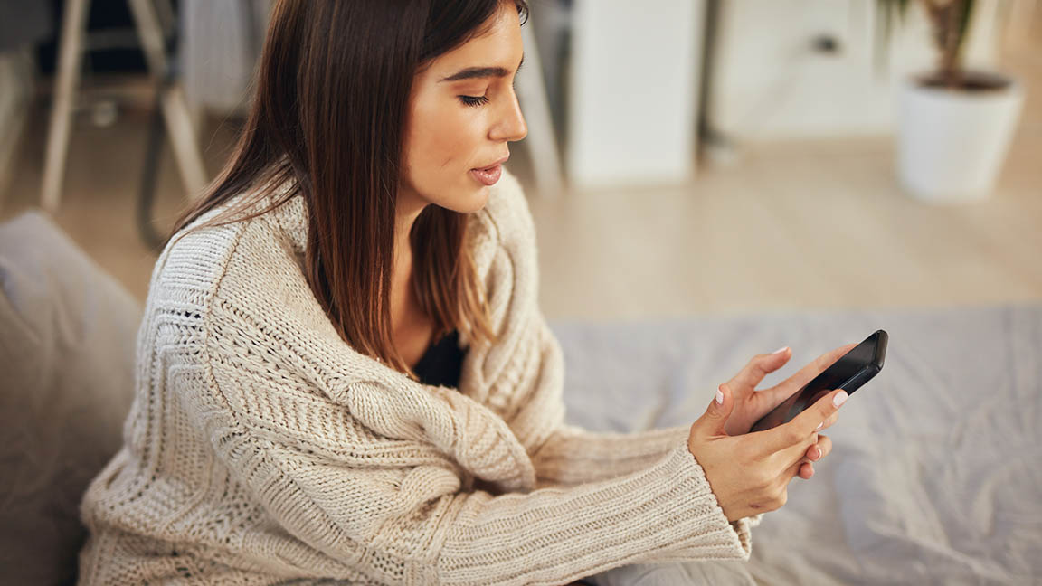 Woman at home using smartphone.
