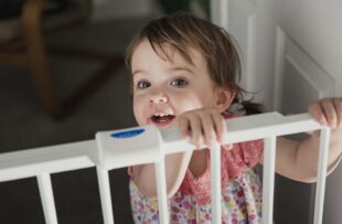 Child standing at baby gate.