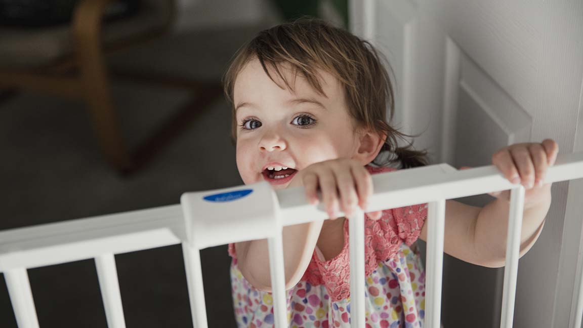 Child standing at baby gate.