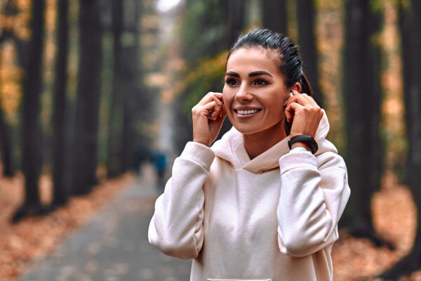 Morning autumn jog. Young woman adjusts headphones before jogging.