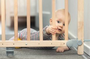 Child playing behind safety gate.