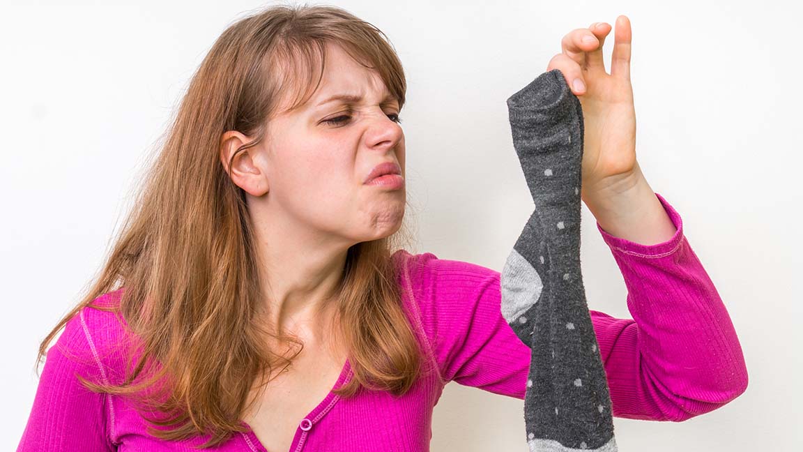 Woman smelling stinky sock.