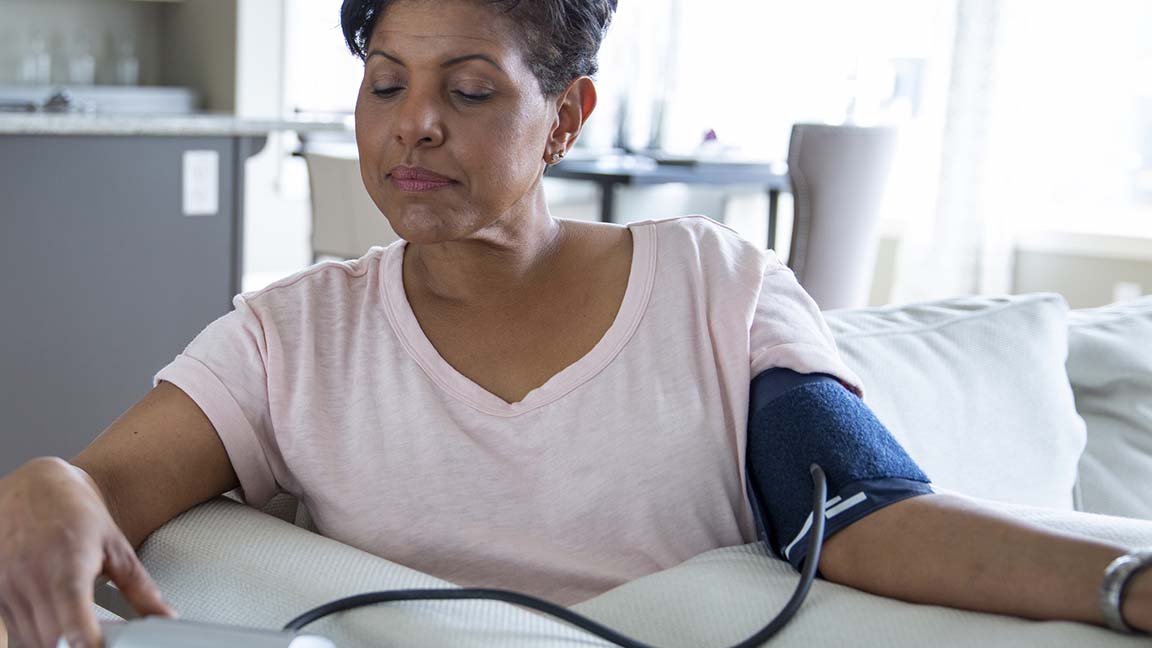 Woman checking blood pressure in living room