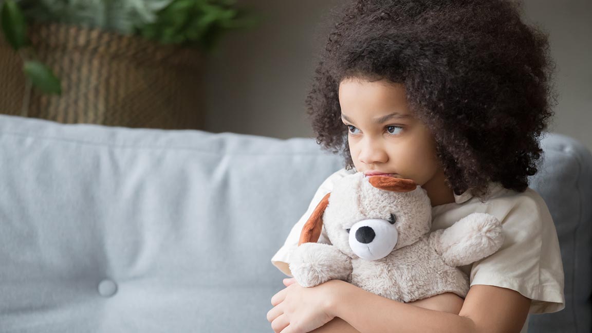 Anxious child holds teddy bear.