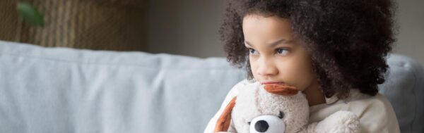 Anxious child holds teddy bear.