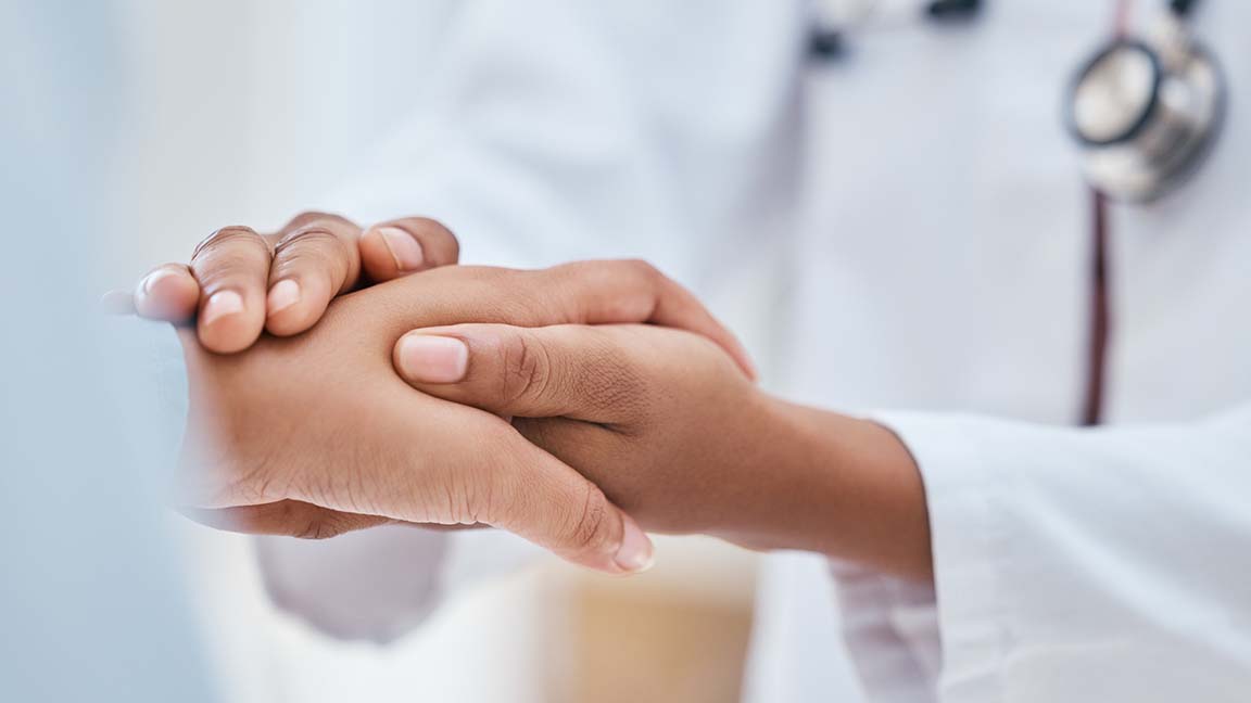 Physician holding patient's hands following diagnosis.